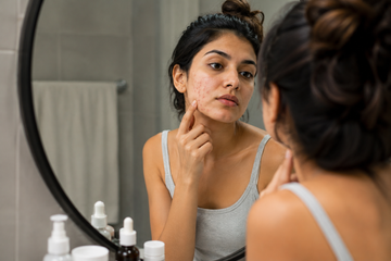 Woman checking skin during a skincare routine to identify purging or breakouts
