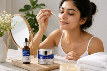 Woman applying retinol facial essence with retinol and collagen skincare products on a bathroom vanity